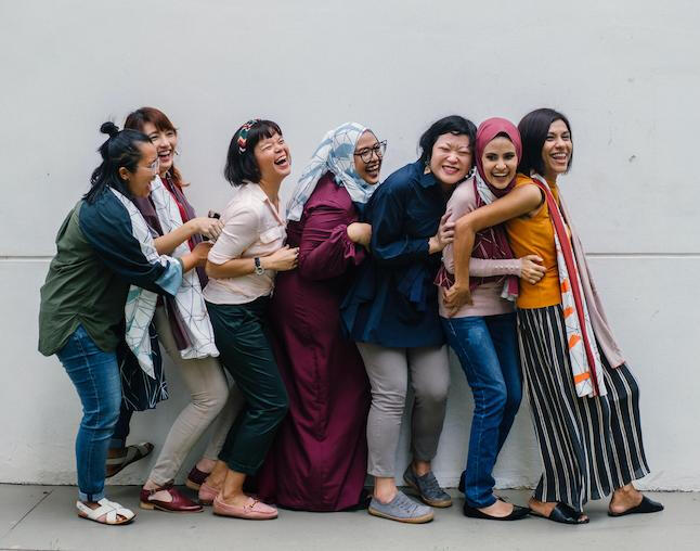 A group of 7 women hugging and laughing